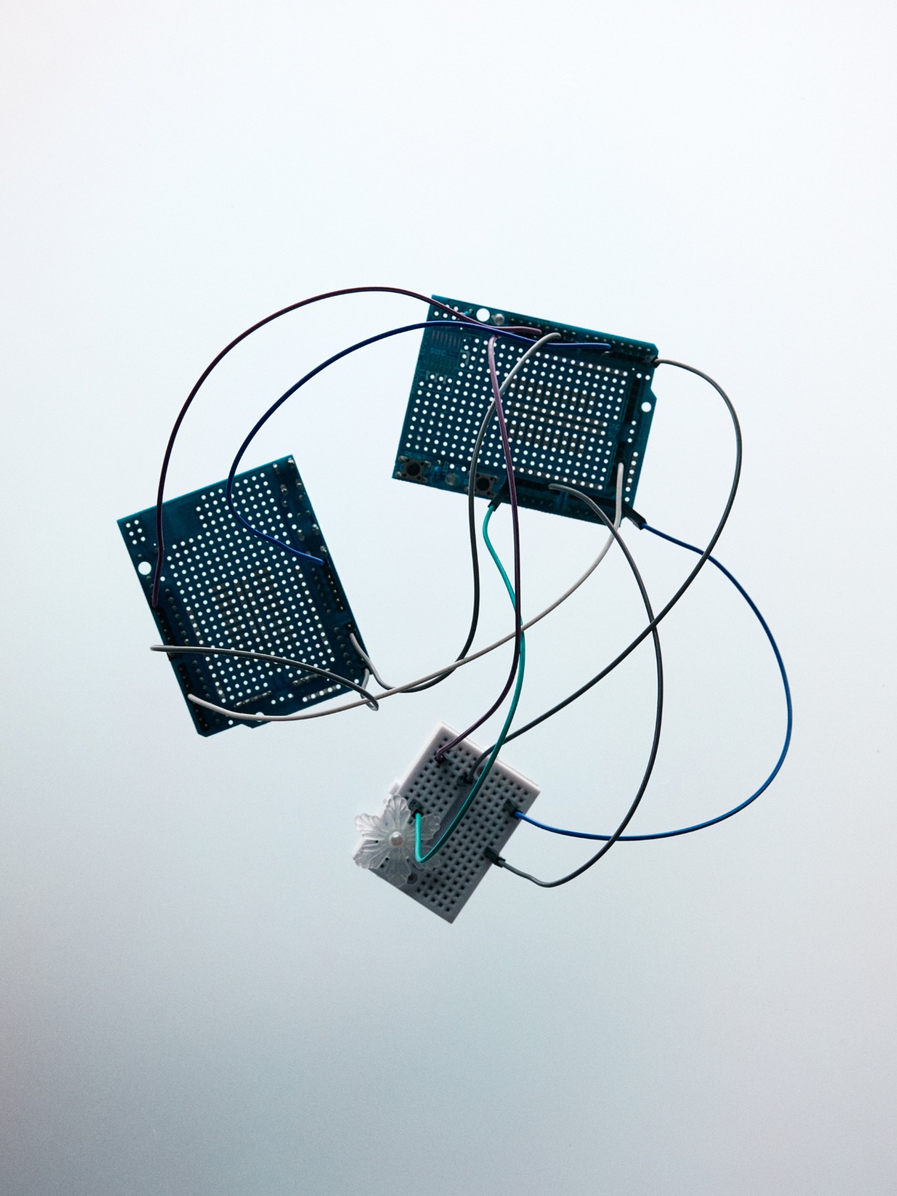 Connected circuit boards suspended against a pale background